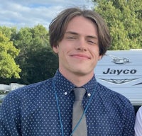 two young men smiling in front of a rv