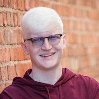 a young man wearing glasses and a maroon hoodie